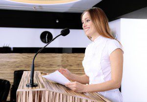 Businesswoman holding a printed speech at the lectern.