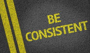 Proofreading for consistency. Shows bright yellow text on a road "Be Consistent".